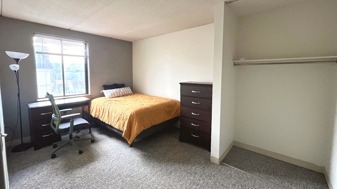 A bedroom with a bed, desk, and chair.